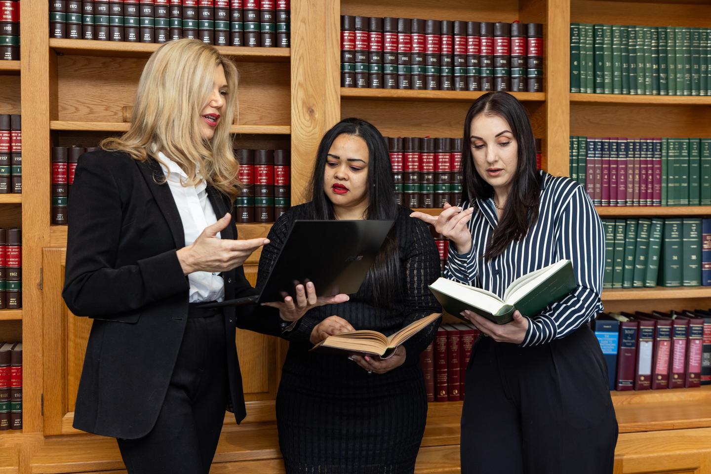 Three attorneys consulting law reports in the firm's library